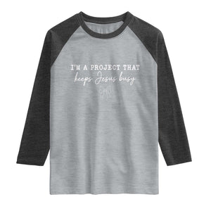 I am a Project That Keeps Jesus Busy Coquette Bow Raglan Shirt Christian Faith Humor TS02 Heather Gray Heather Charcoal Print Your Wear